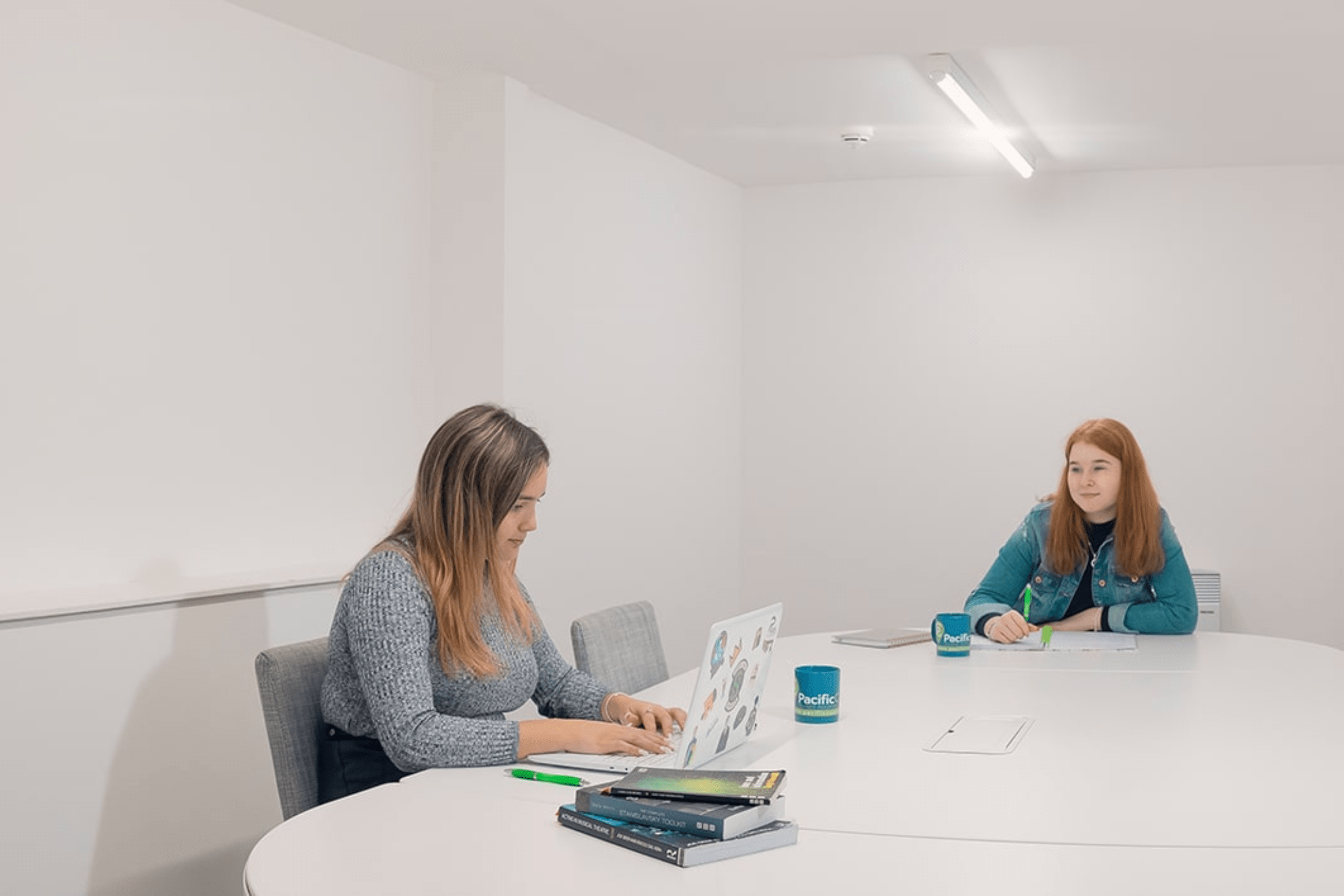 Bedroom with white bed, dark brown runner, wood floor, and modern bathroom with glass door
