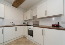 White house with blue roof and green garden in front, sunny day